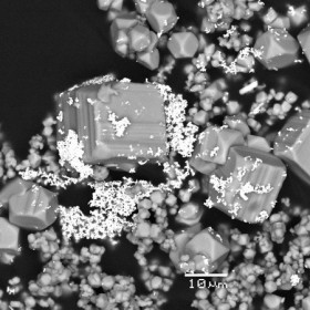 Nanoparticules d’or (points brillants) et cristaux de pyrite (gris), obtenus à partir d’une solution de soufre et d’or en laboratoire. / CNRS